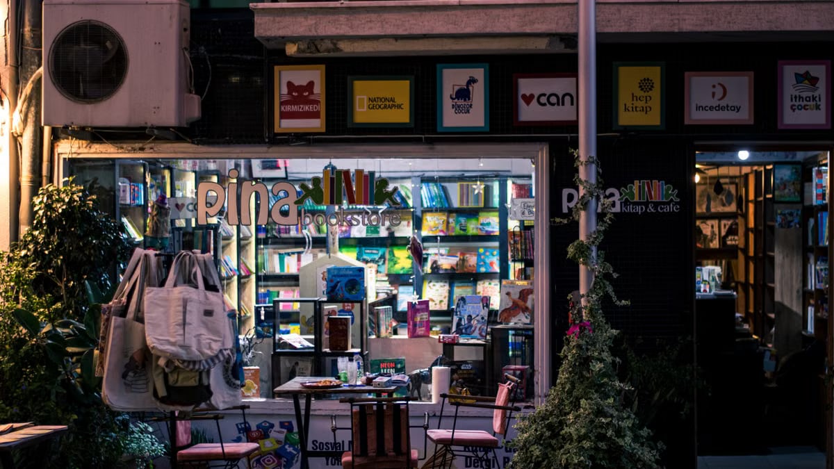 Charming nighttime bookstore and cafe scene, inviting ambiance with outdoor seating and books on display.